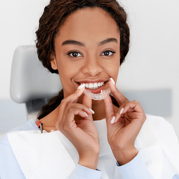 A woman holding Invisalign aligners